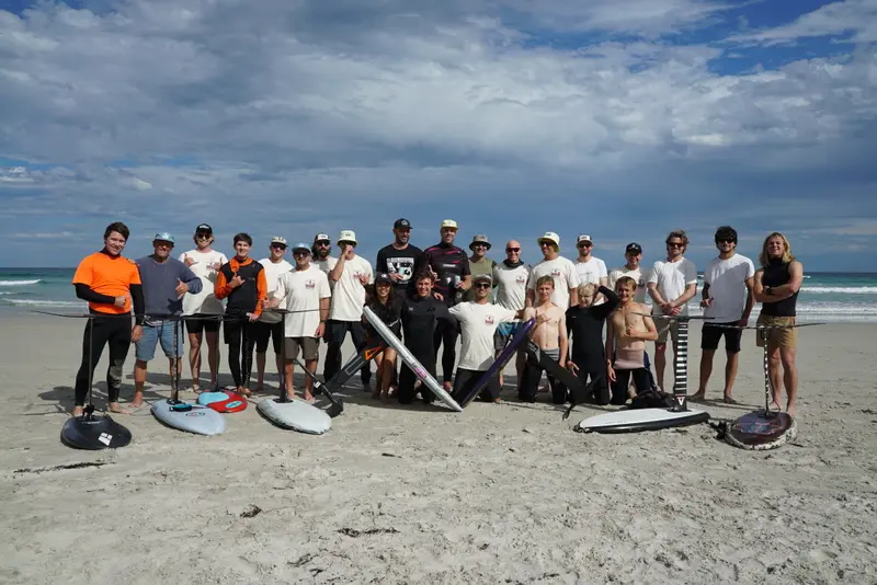 A group of foilers relax together on the beach between sessions