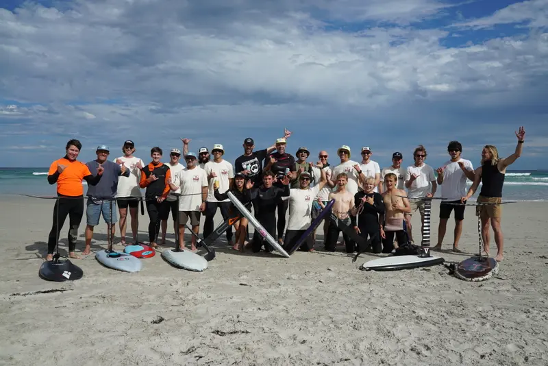 Foilers relax together on the beach after a session
