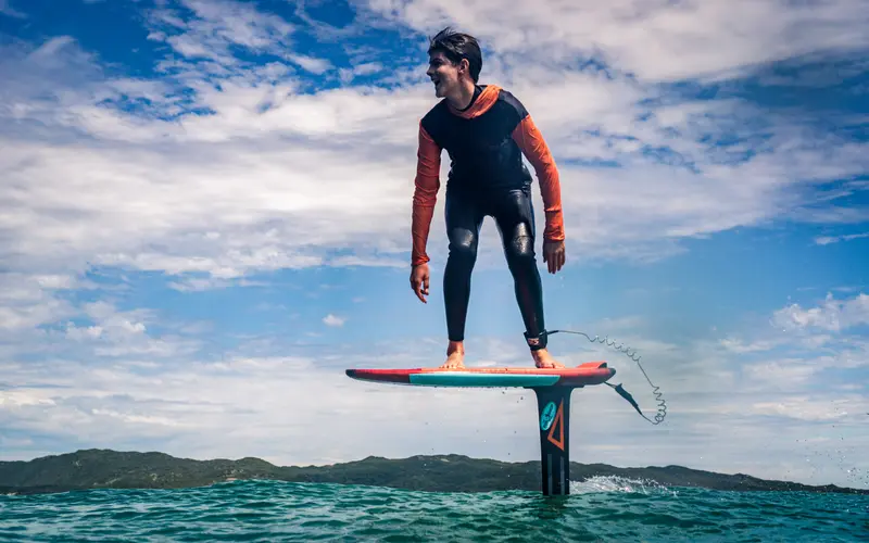 A prone foiler pumps along a clean green wave face