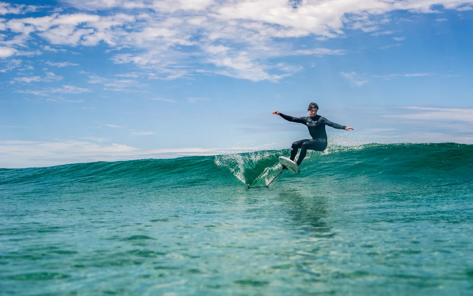 A prone foiler carves a turn on a clean wave